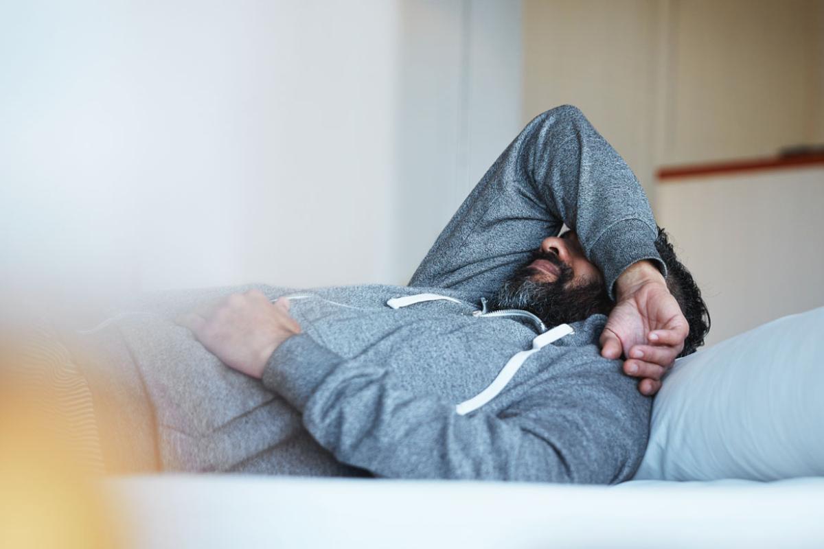 Man laying down covering his face with his arm