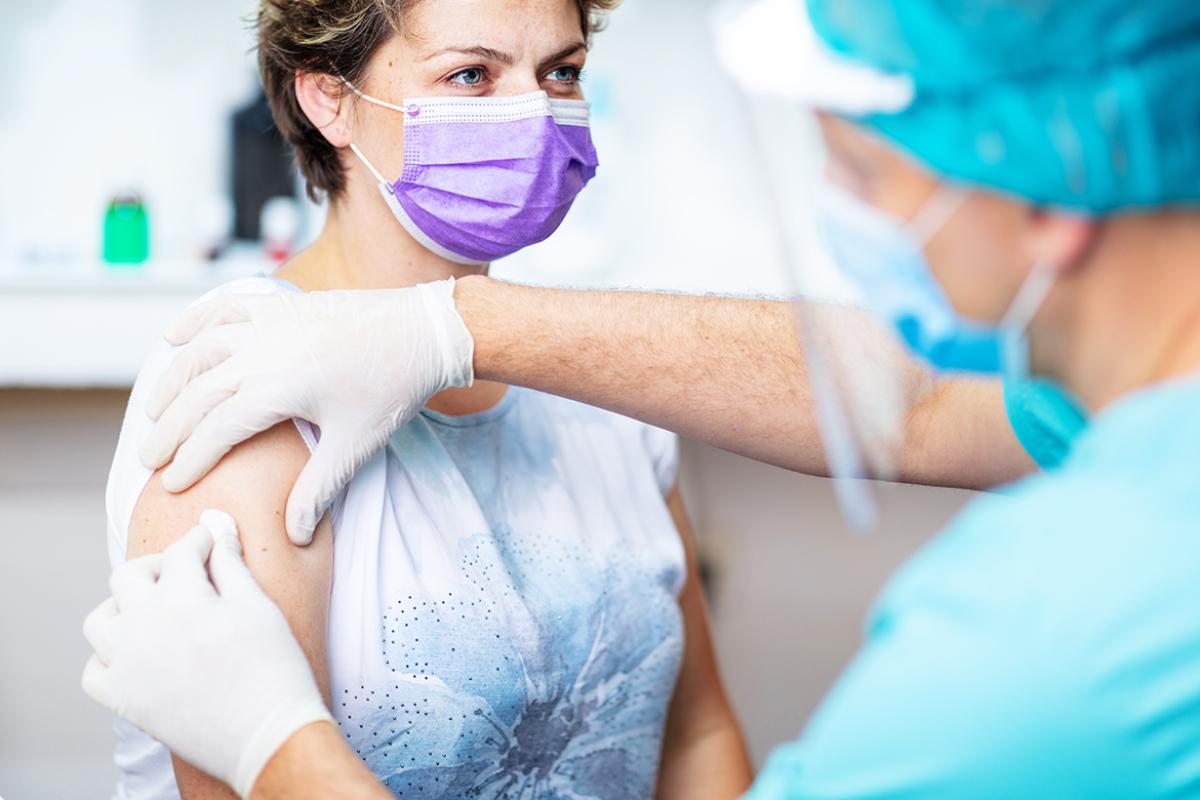 Physician disinfecting a patient's arm with cotton pad.