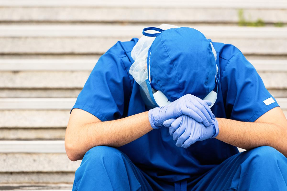 Health care worker holding head in hands