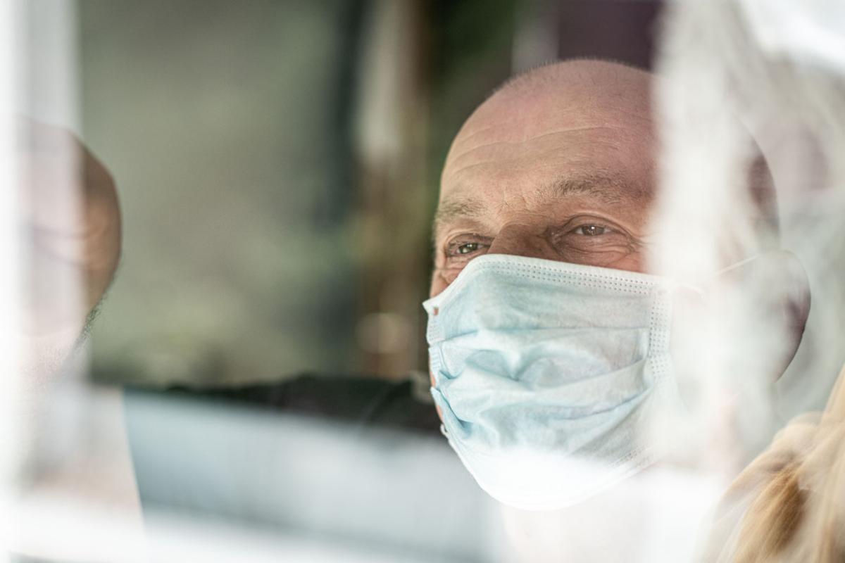 Person wearing a face mask and looking out a window
