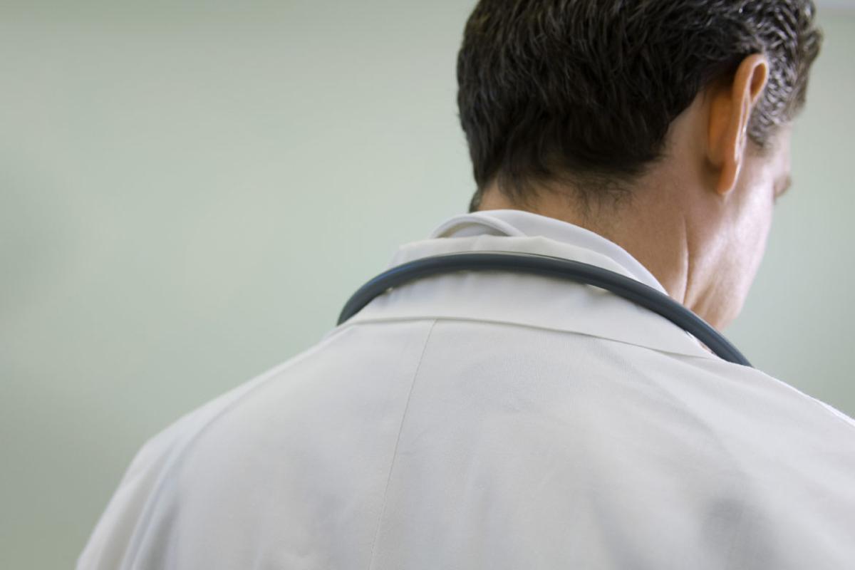 Photo of a doctor, head and shoulders, taken from behind.