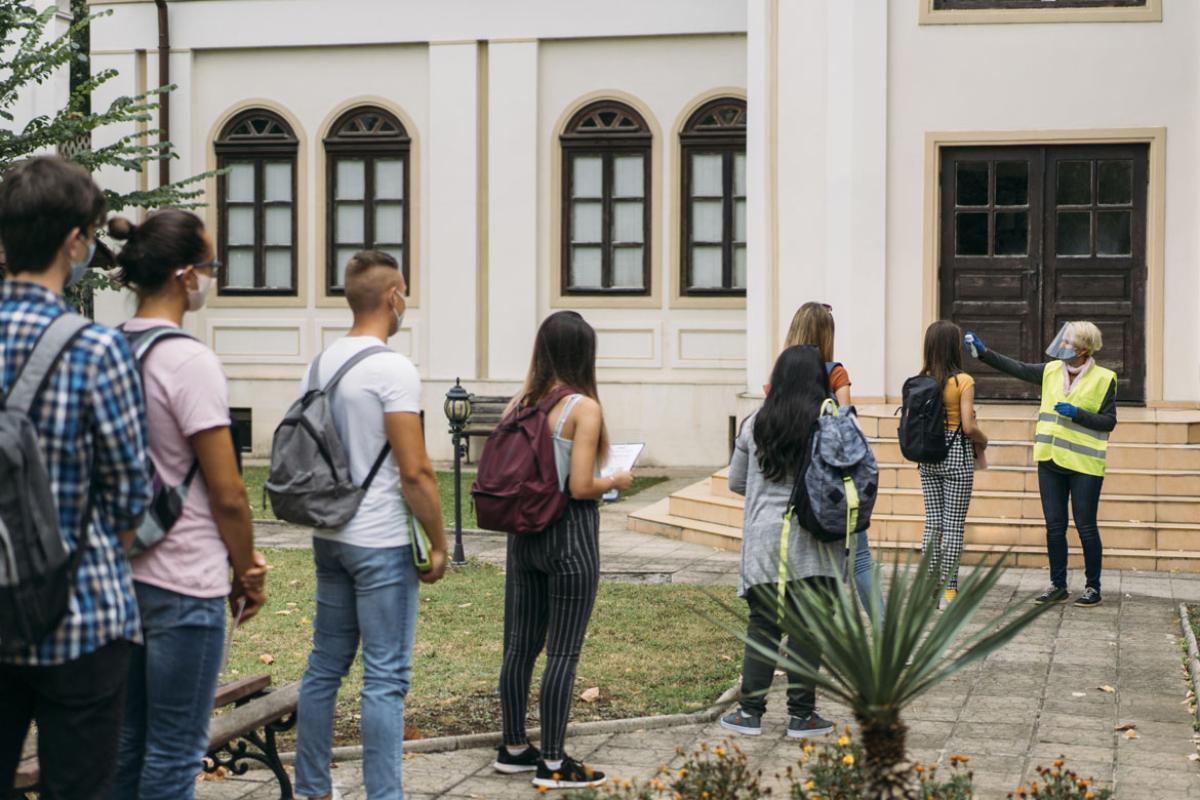 Students waiting in line for their temperatures to be checked before entering their school.