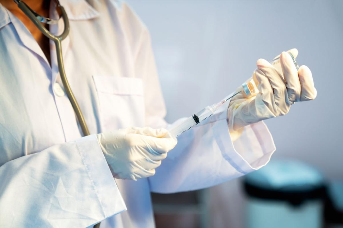 Physician holding syringe in gloved hands