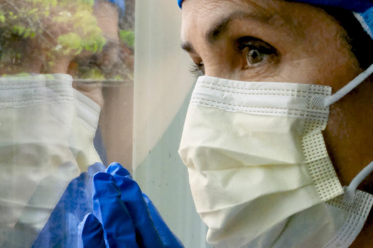 Person wearing a face mask looking out a window