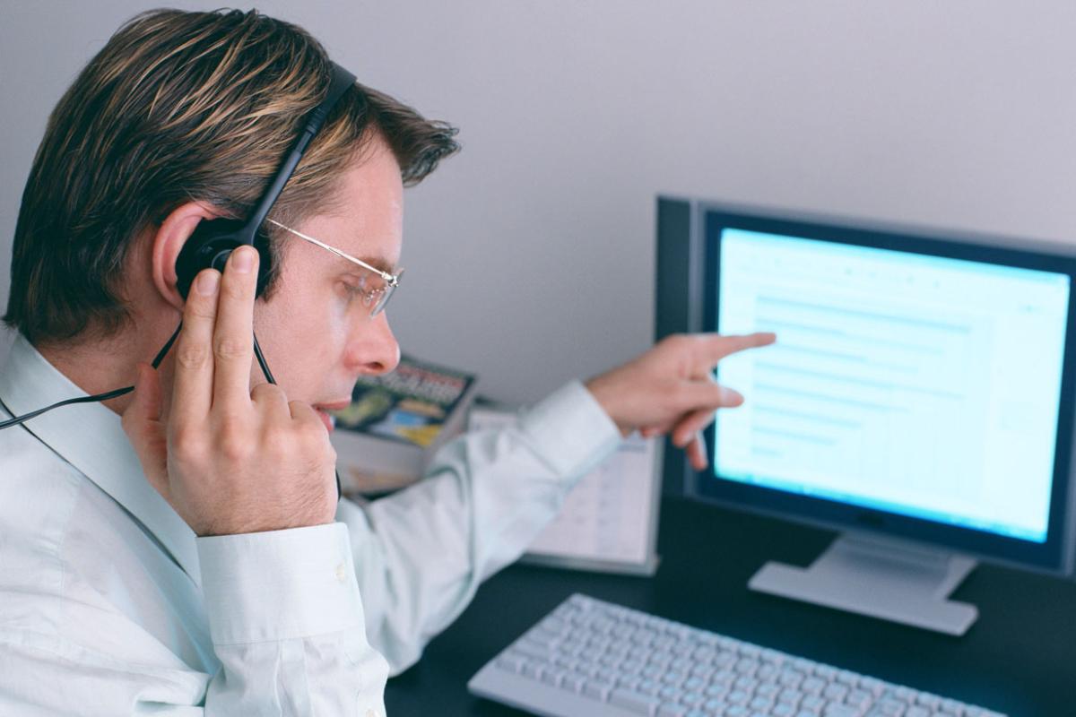 Man talking into a headset while working at a laptop