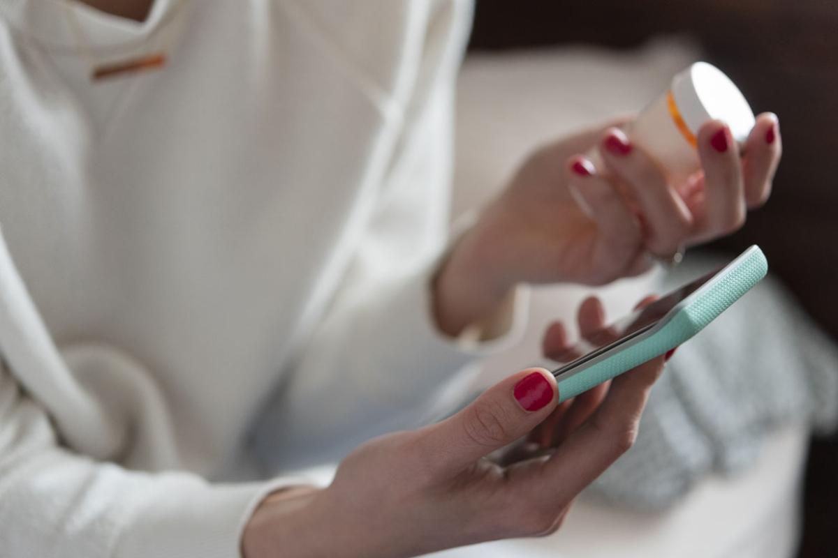 Person holding smart phone and prescription bottle