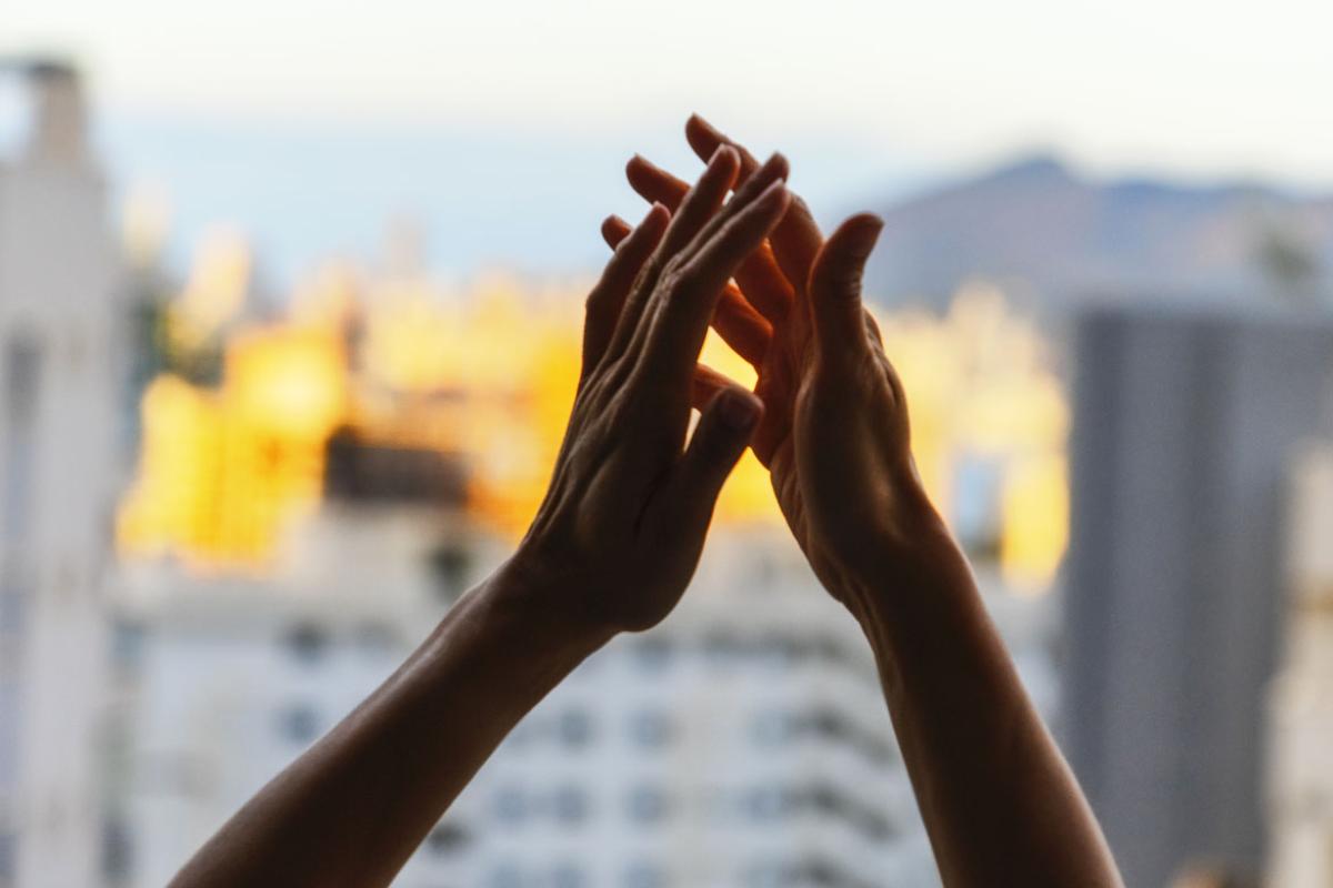 Hands raised in gratitude in front of window