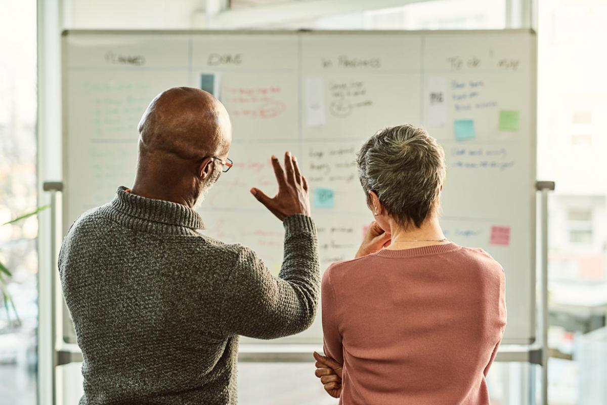 Two people looking at a white board
