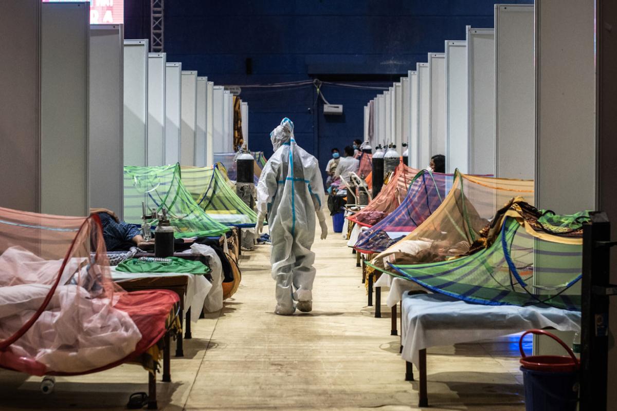 A medical worker in PPE observes patients 