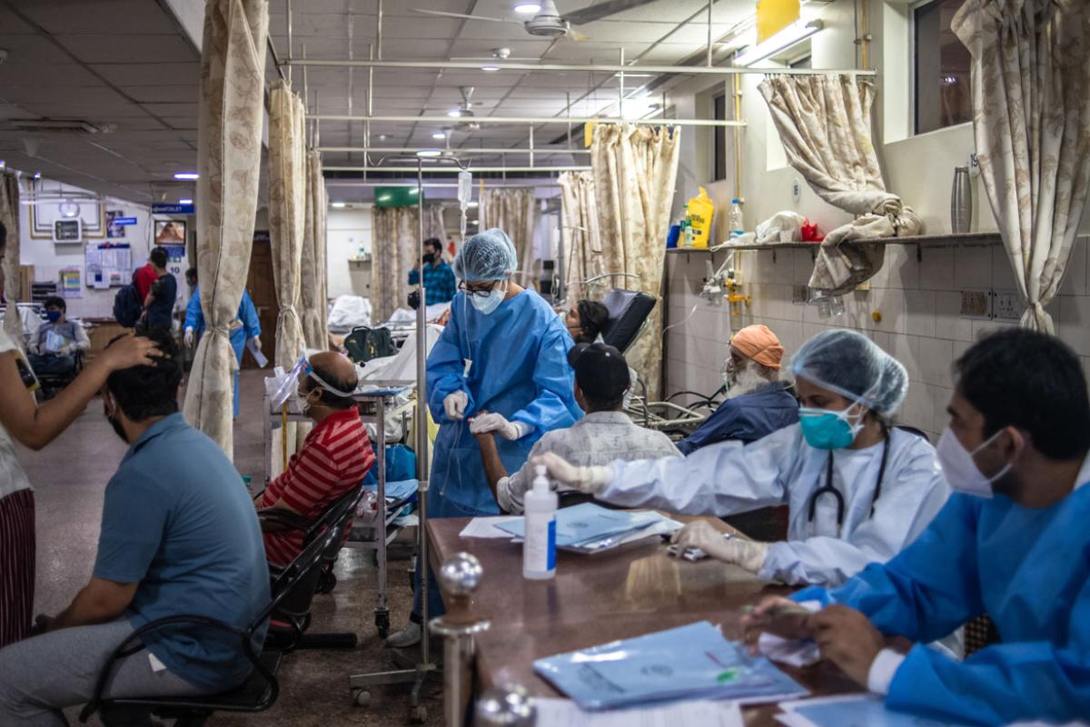 Room filled with physicians and health care workers treating patients, all wearing masks.