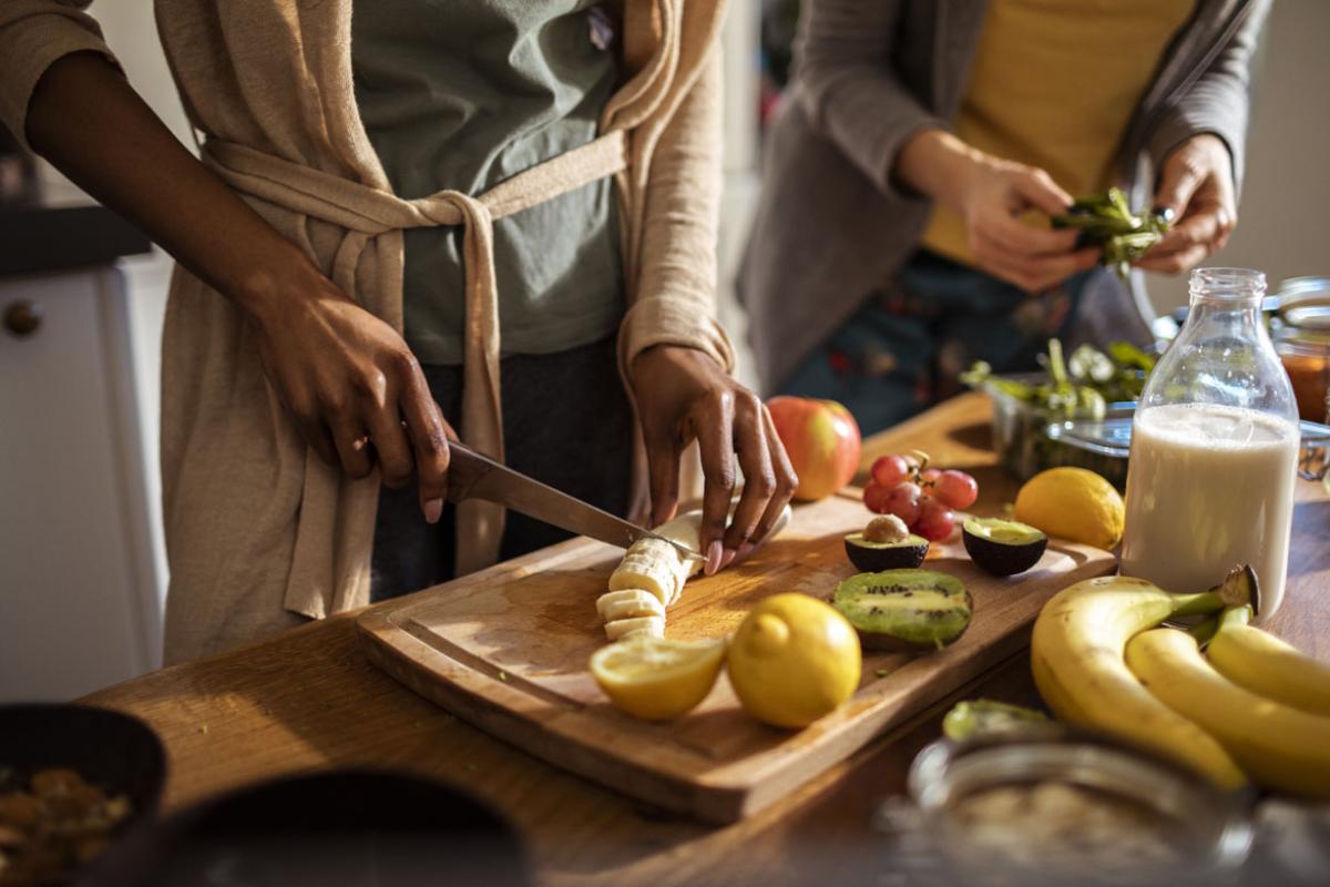 People cutting fruit in a kitchen