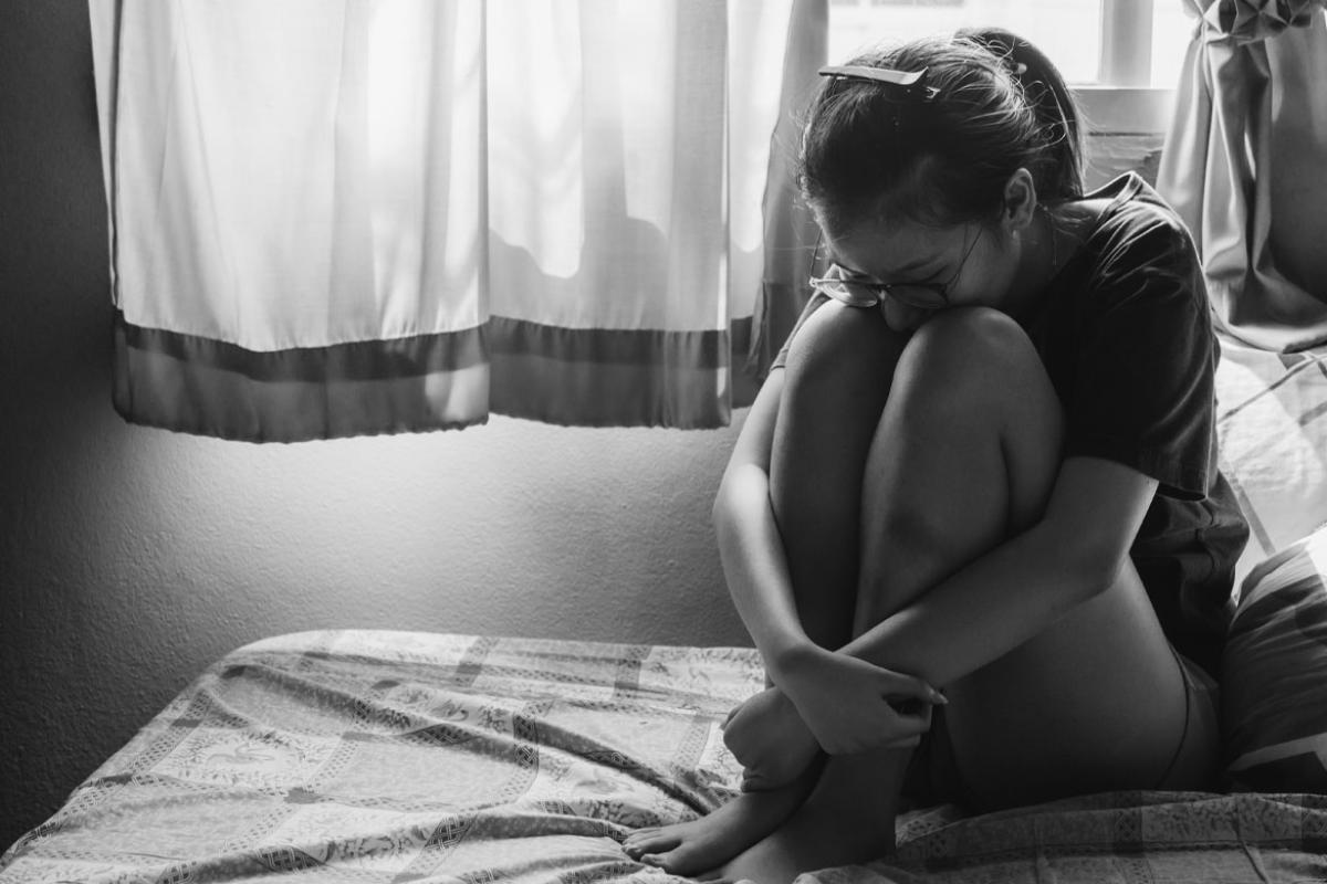 Person sitting alone in a dark bedroom