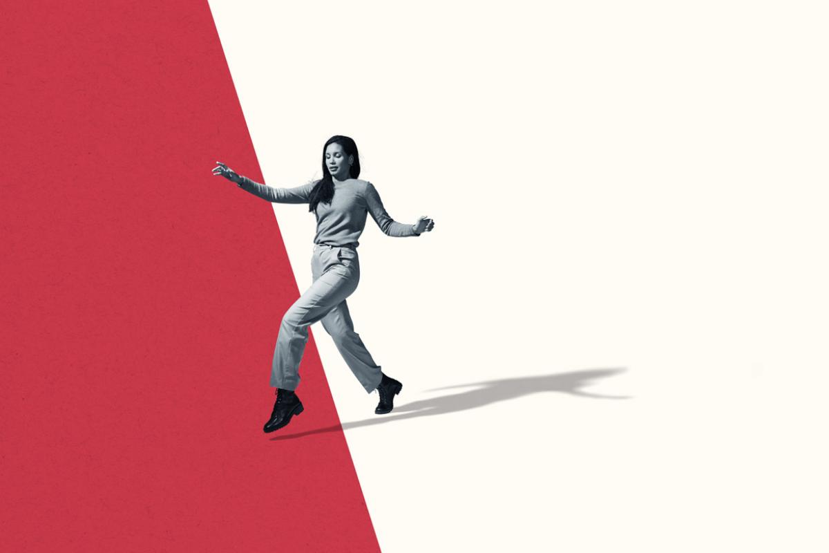 Photo illustration of a woman in black and white crossing the background which is divided diagonally with white on the left and red on the right.