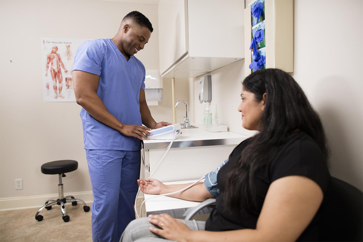 A woman having her BP taken as a health care working monitors it.