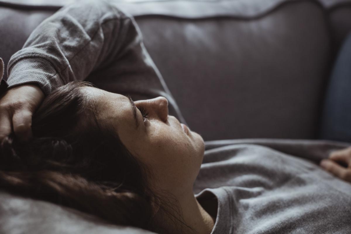 Woman laying down face up on couch looking into the distance