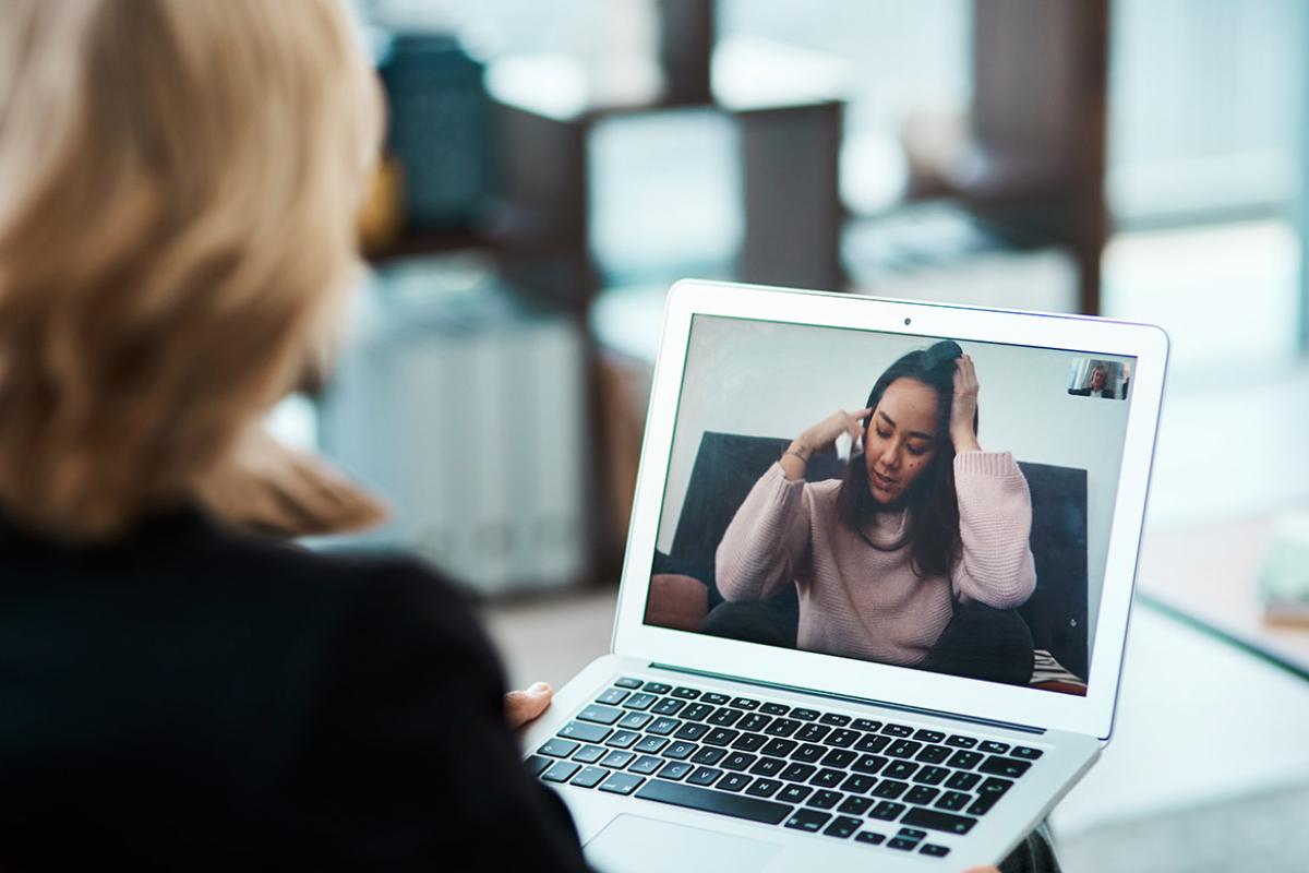 Two women on a teleconference call using a laptop.