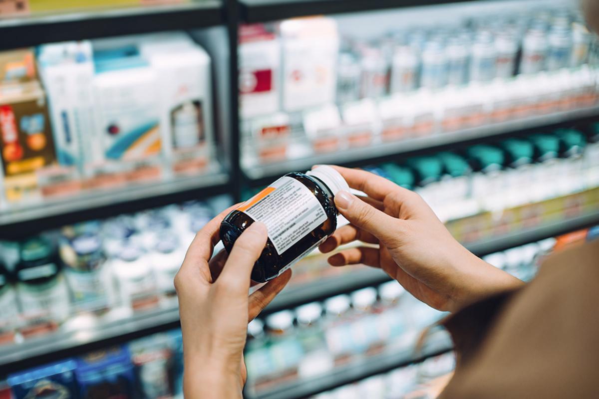 Tight shot of person reading label on vitamin or supplement bottle