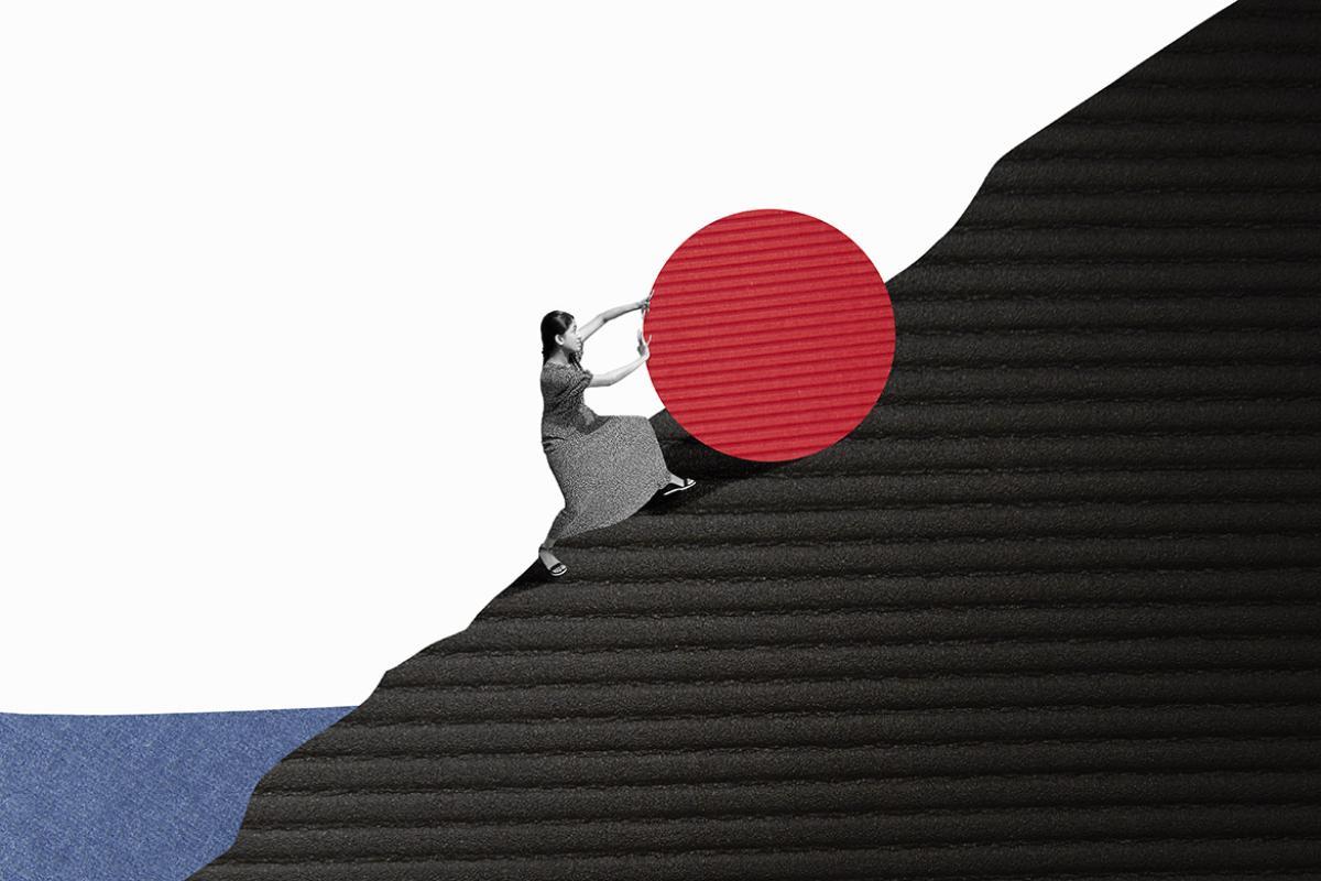 Woman pushing a large red ball up a hill or mountain