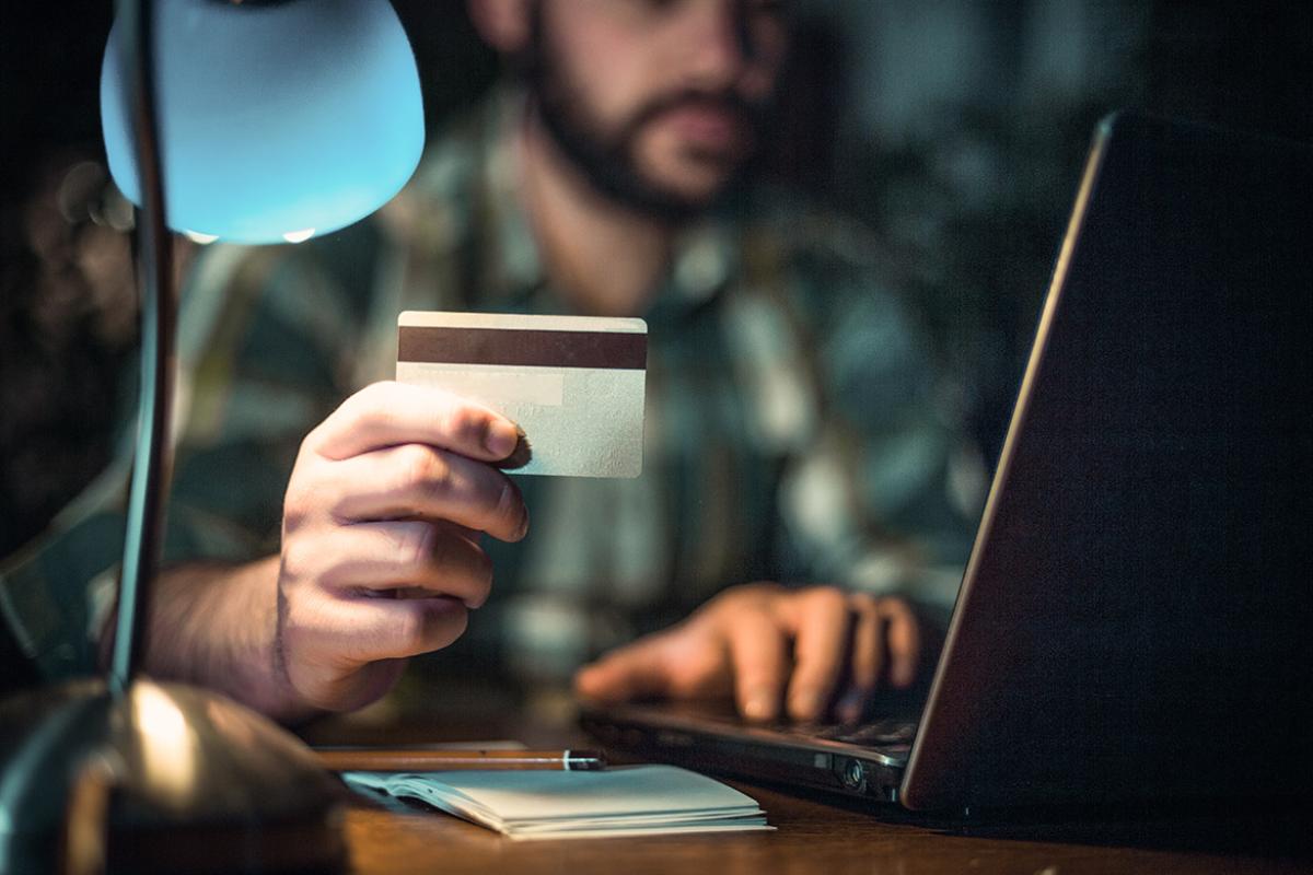 Man with credit card in his hand paying bills or purchasing items online using a laptop