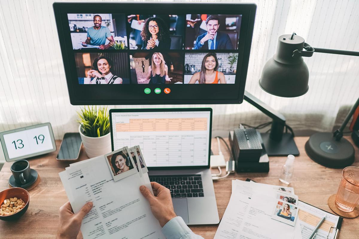 Manager reviewing applications while holding a virtual conference call with job applicants on a laptop