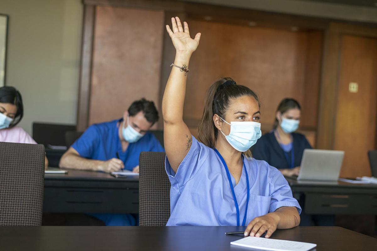 Person in a classroom raising their hand