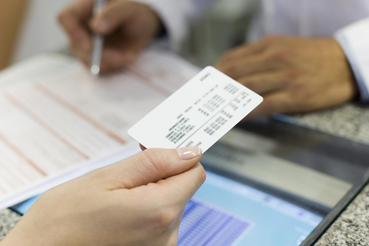 Tight shot of person's hand presenting an insurance card at a medical appointment