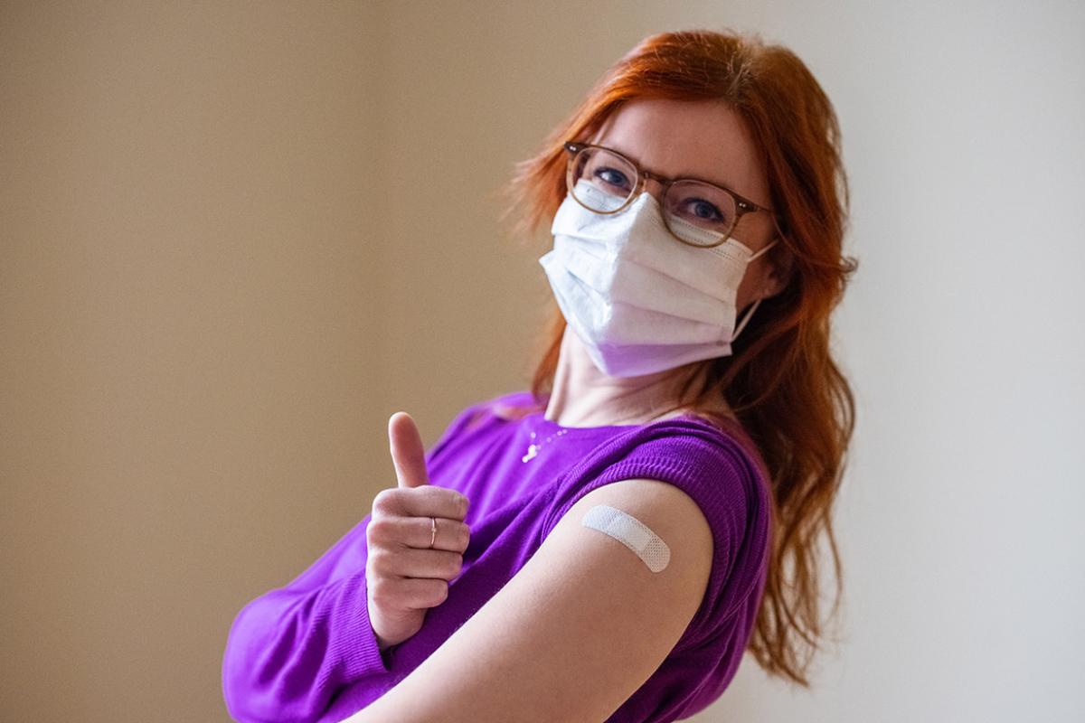 Person wearing a mask giving a thumbs up