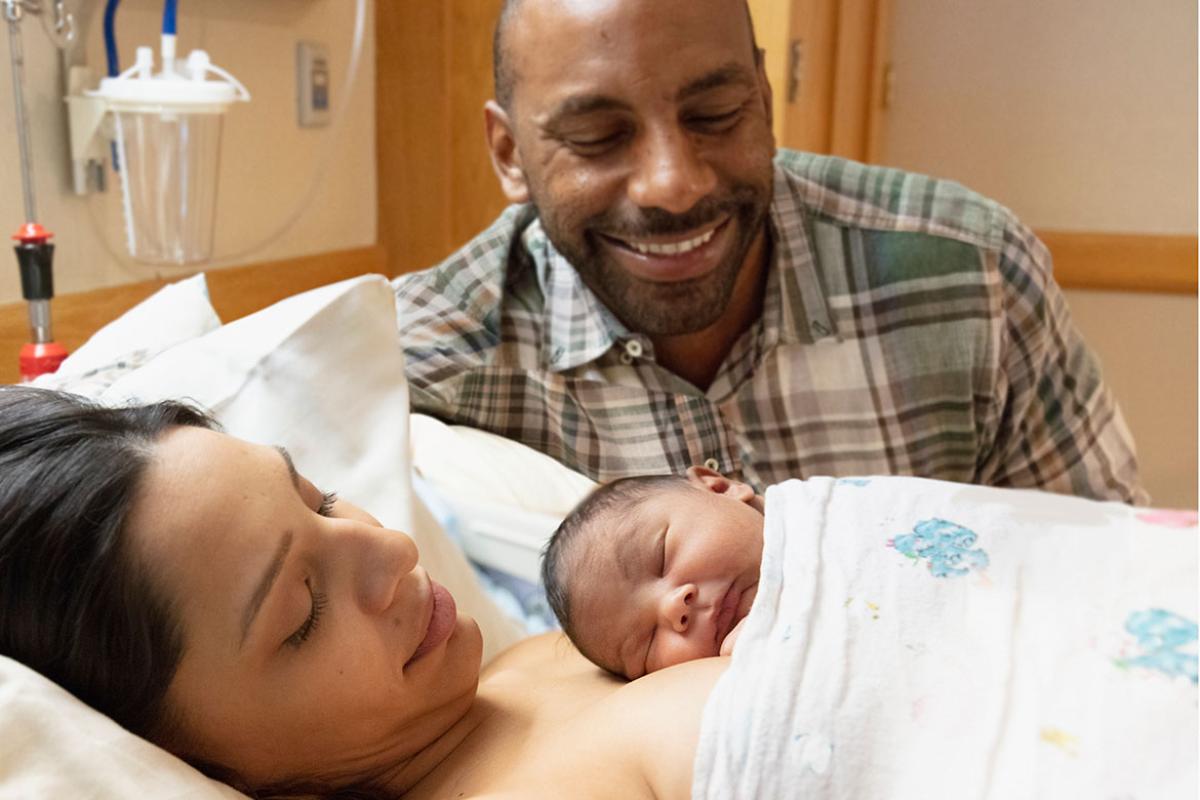 Smiling family cradling a newborn baby