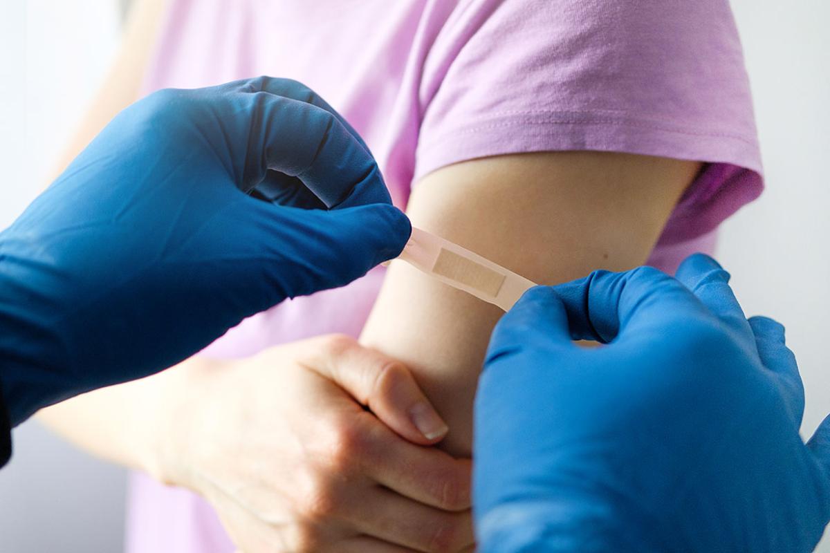 Health care worker putting bandage on child's arm