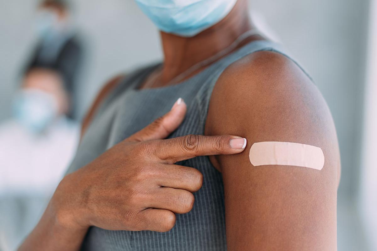 Person pointing at bandage on arm