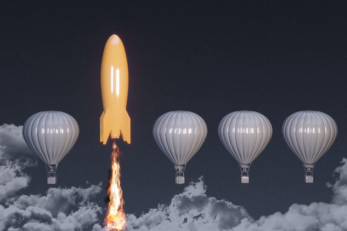 Orange colored rocket rising on the top between the hot air balloons