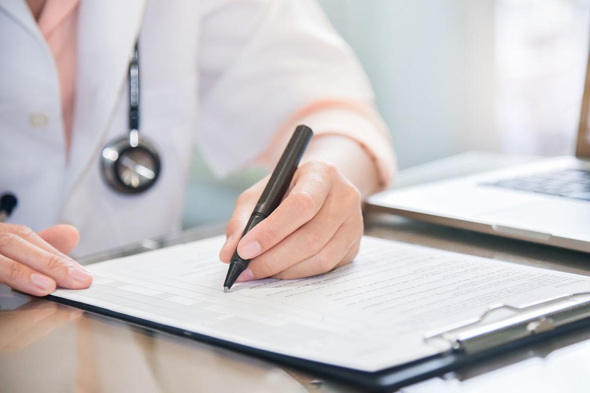 Physician writing notes on a clipboard