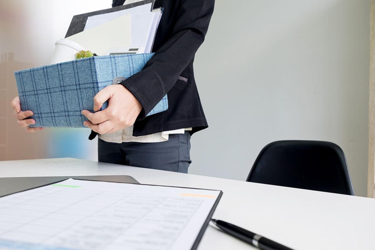 Person holding a box filled with office supplies