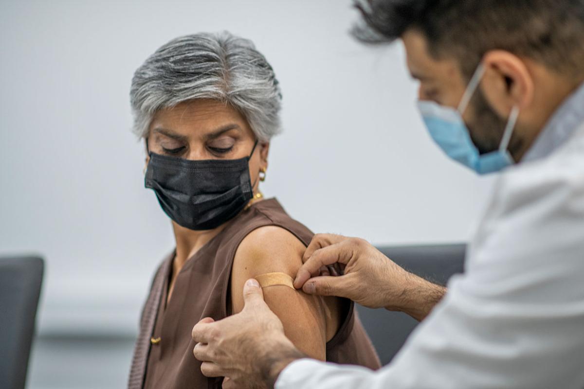 Person receiving a bandage on their arm after a medical injection