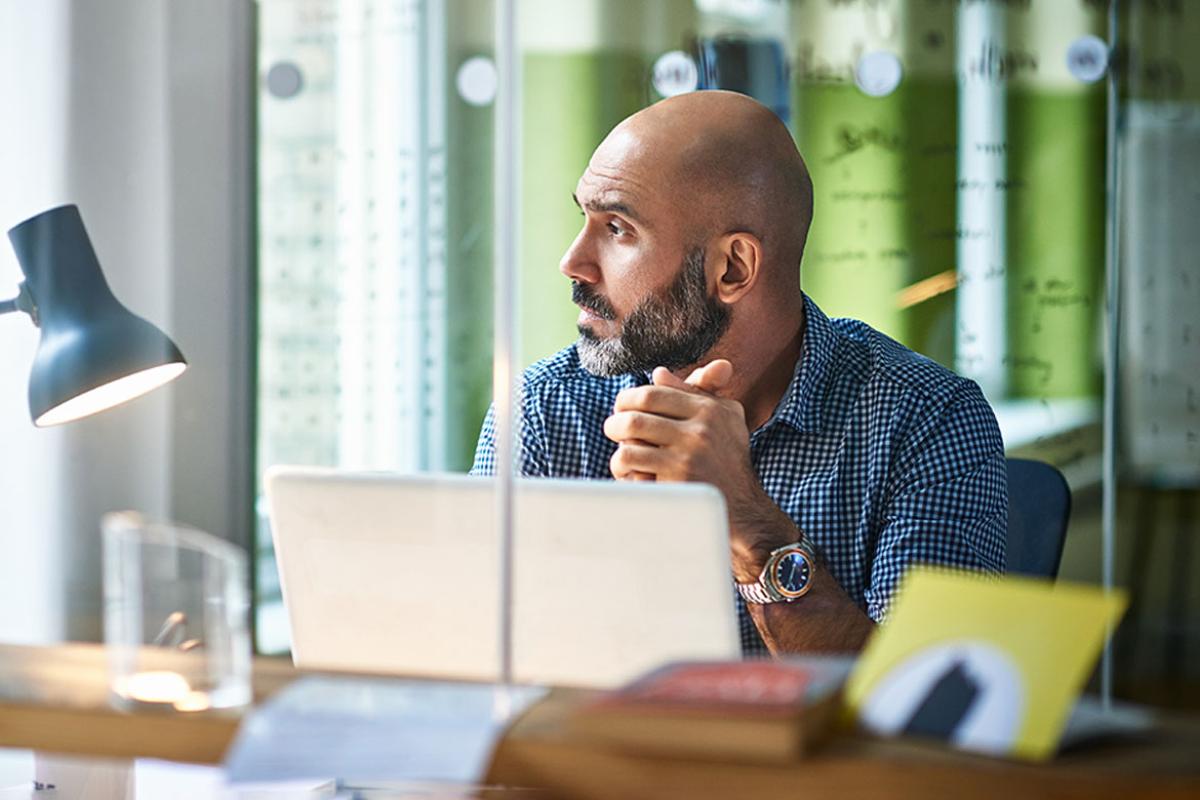 Person in front of a laptop, gazing out a window
