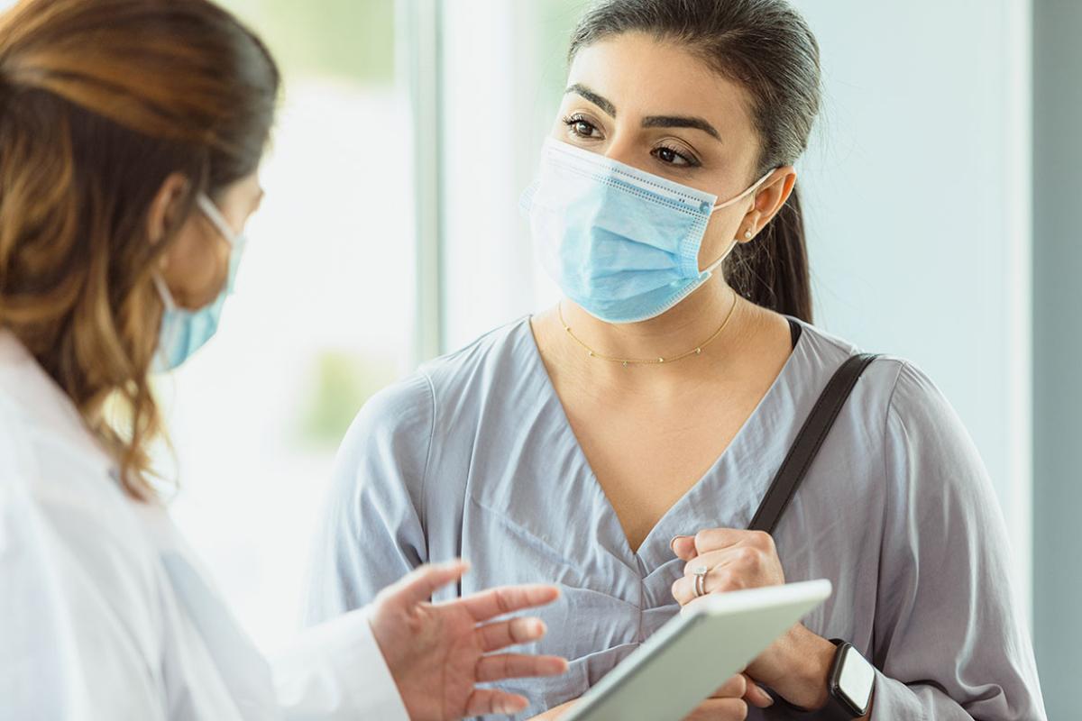 Masked physician and patient in discussion