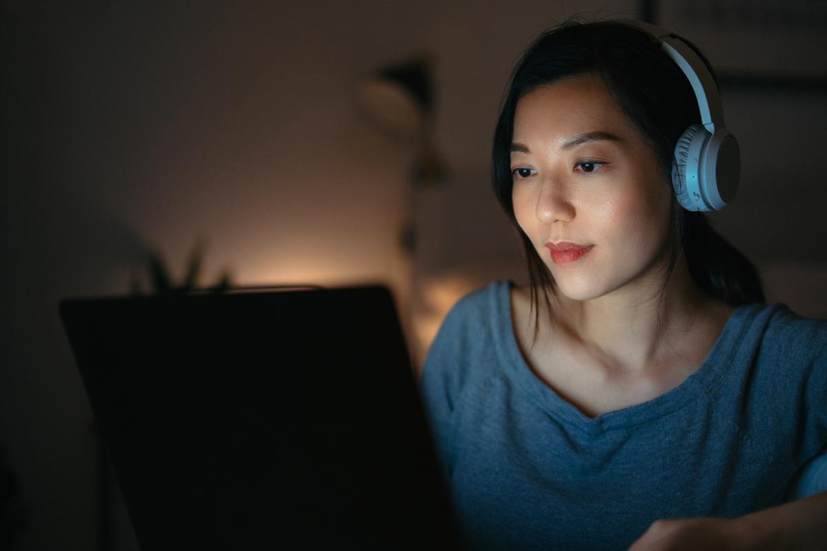Person wearing headphones and looking at laptop screen