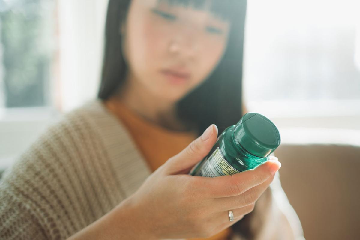 Person reading the label on a bottle of supplements