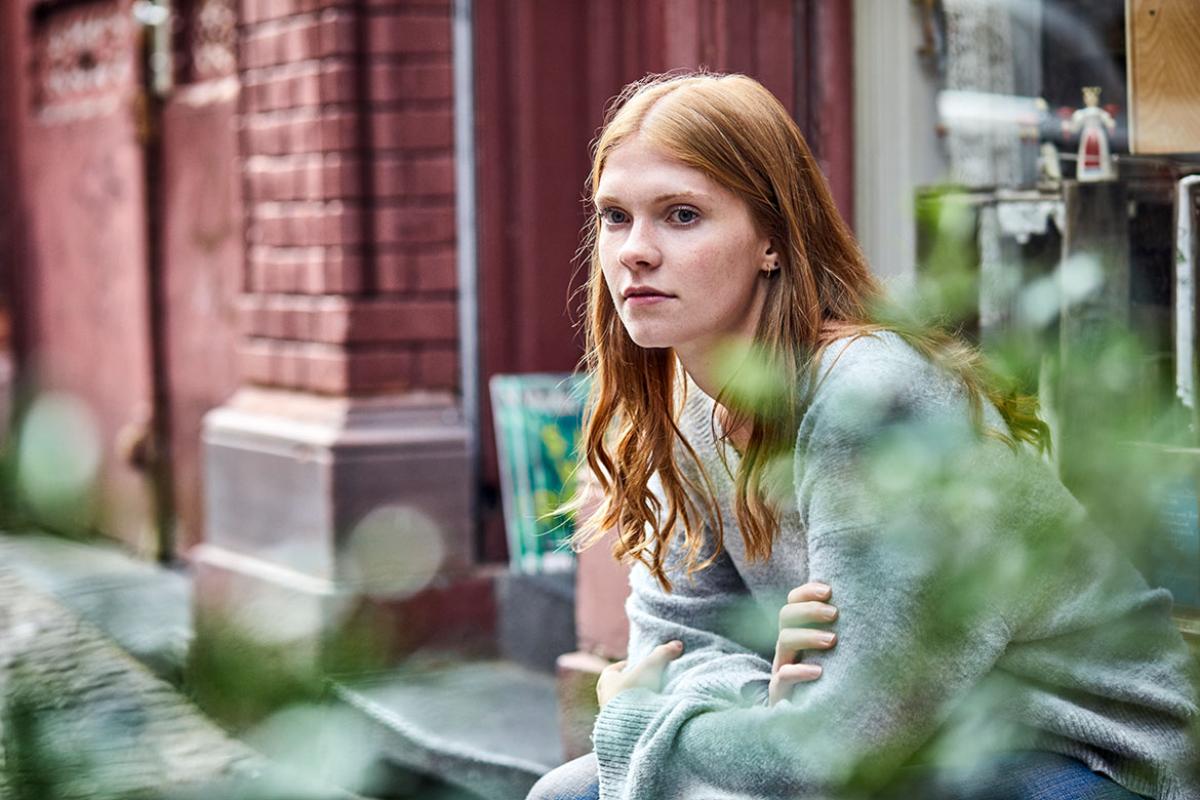 Young person sitting on a stoop and looking into the distance