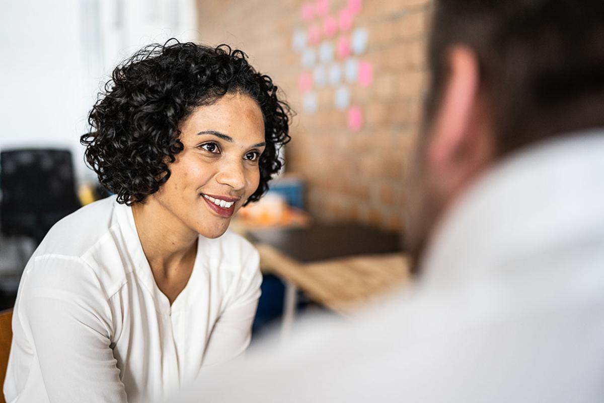 Person smiling and listening to another individual