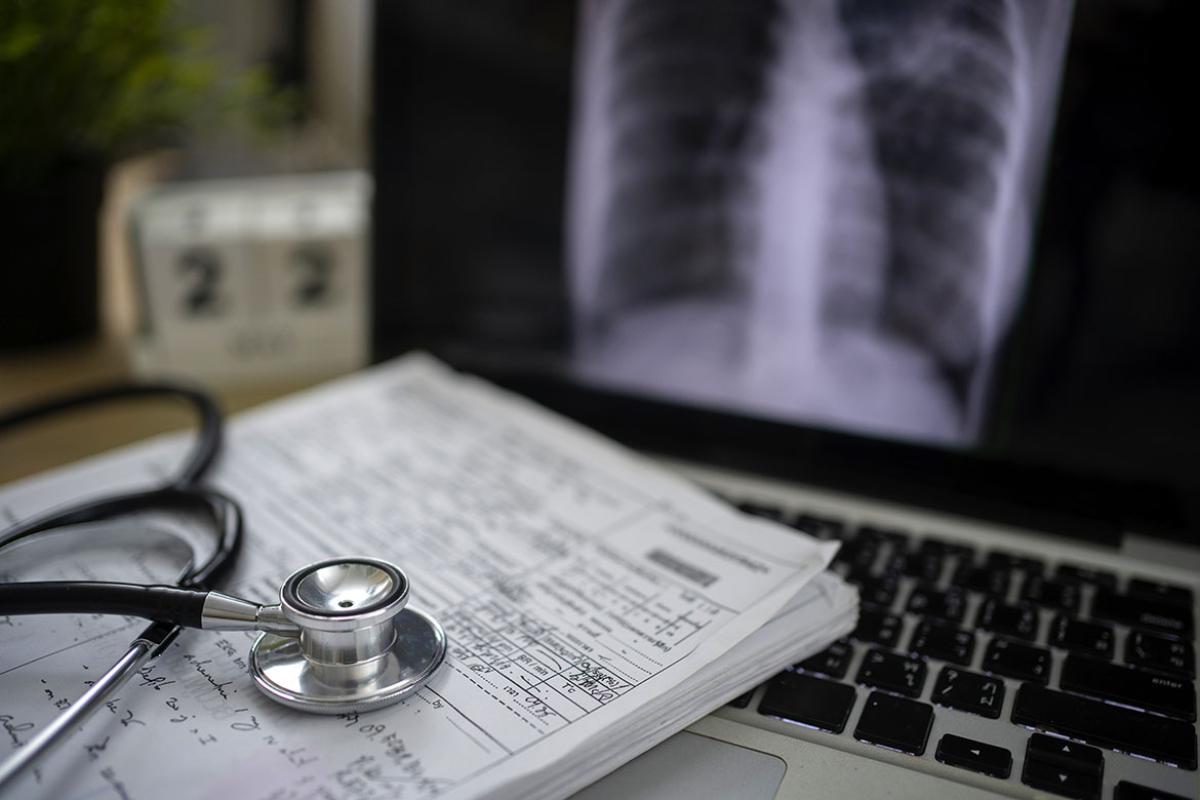 Stethoscope and stack of documents on a laptop computer