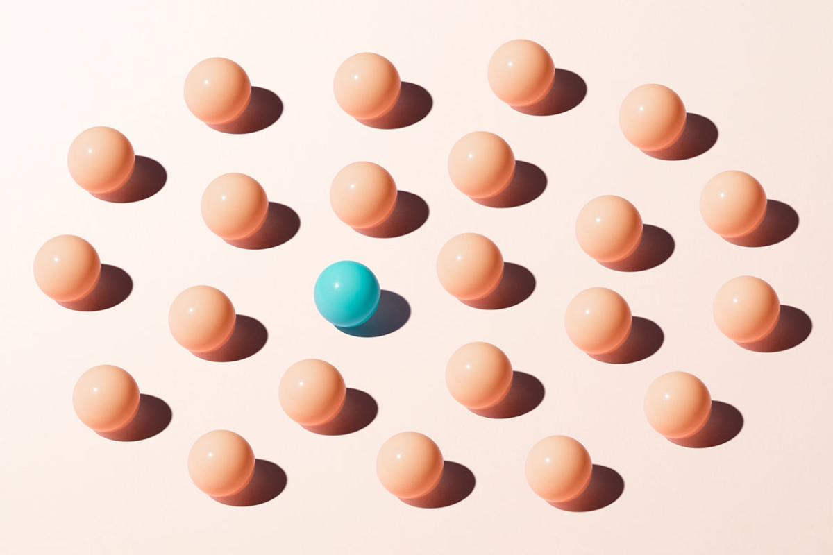 Turquoise colored sphere among peach colored spheres