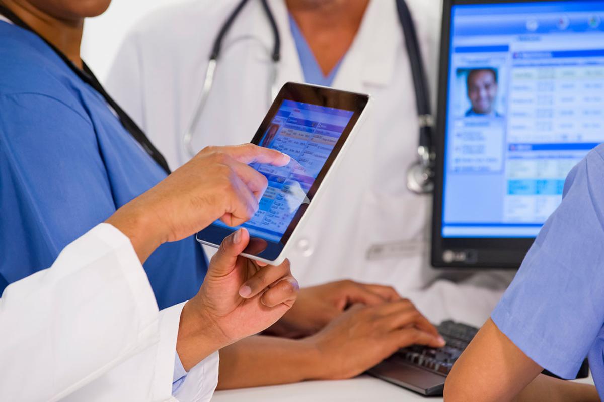 Group of health care workers using tablets and a desktop computer