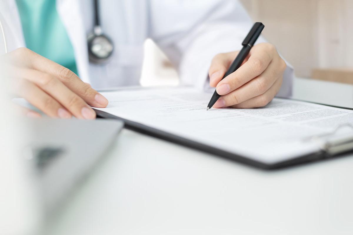 Health care worker writing notes on a clipboard