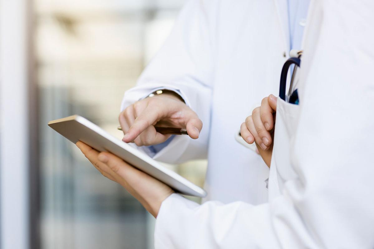 Finger pointing at a tablet that another person is holding
