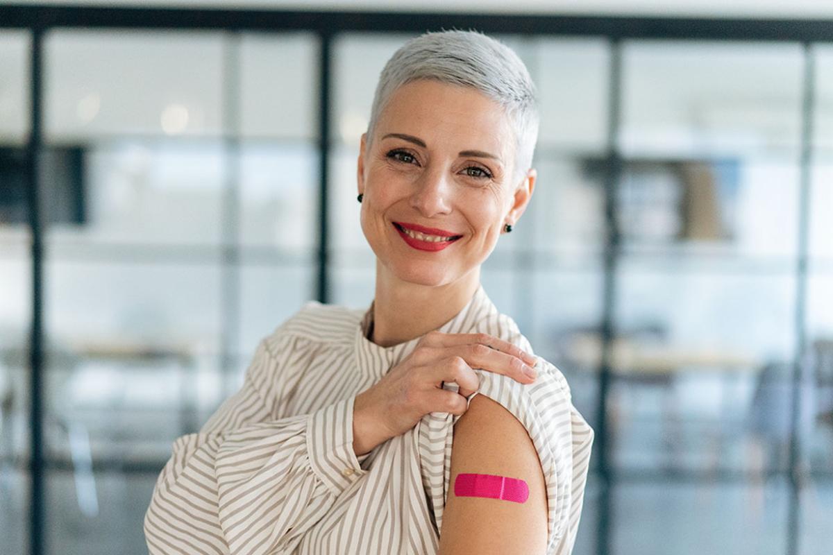 Smiling person showing their upper arm with adhesive bandage