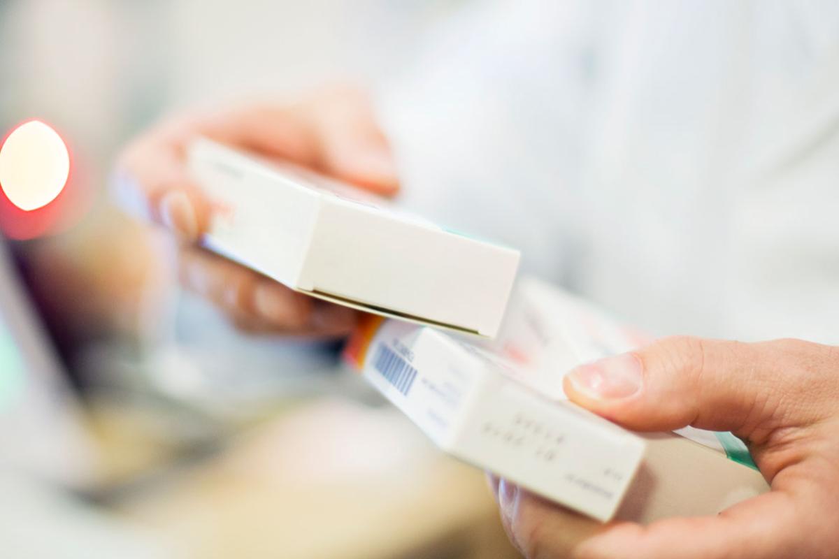 Hands holding two boxes of medications