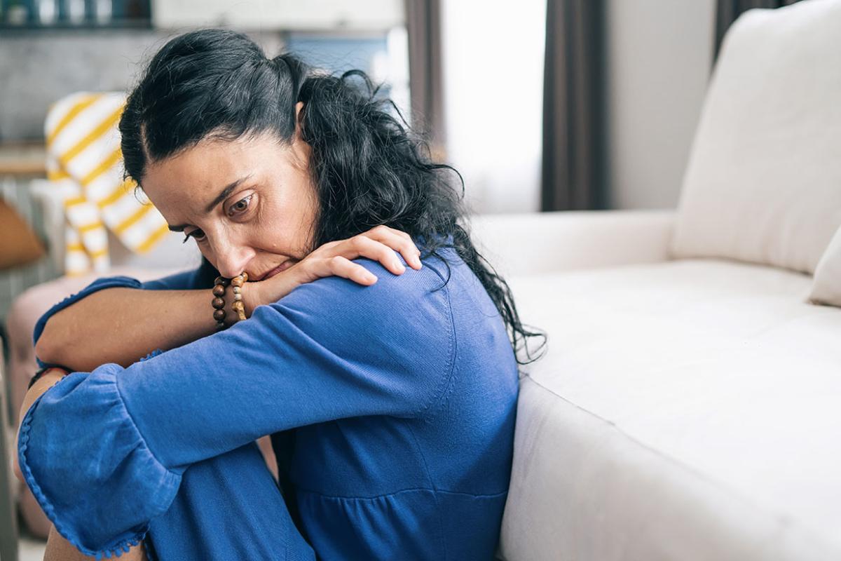 Person sitting on living room floor with head on arms