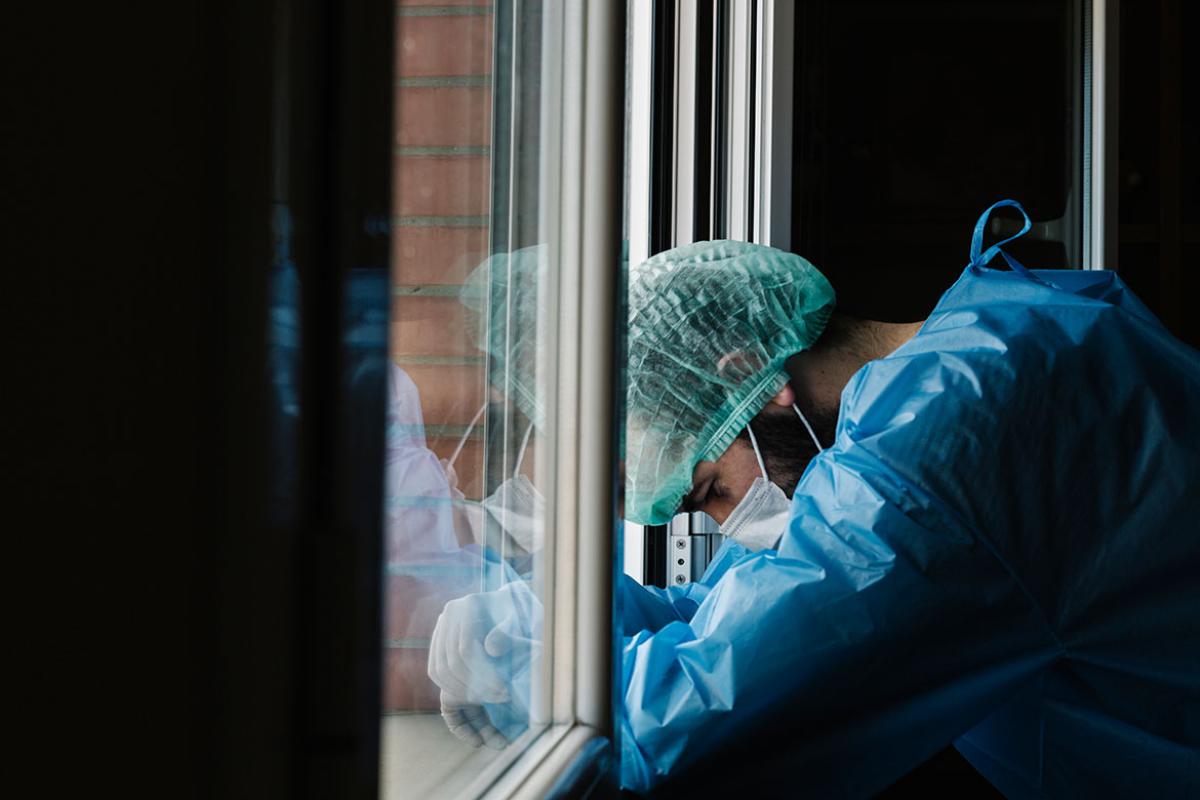 Health care worker slouched in front of window