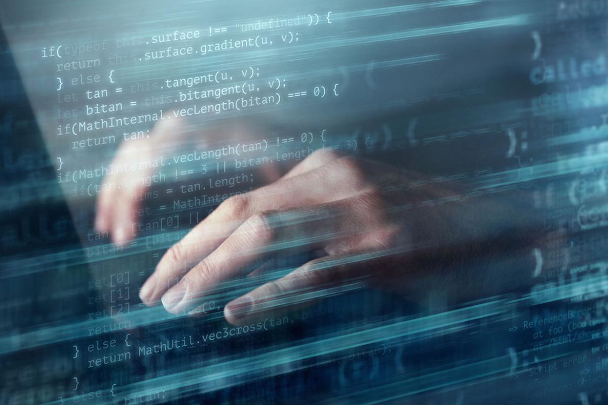 Hands on a laptop keyboard superimposed over multiple lines of computer code